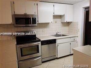 A kitchen features white cabinets, stainless steel appliances, and a tiled backsplash — 6943 SW 40th St # R, Miramar FL 33023, MIRAMAR, FL