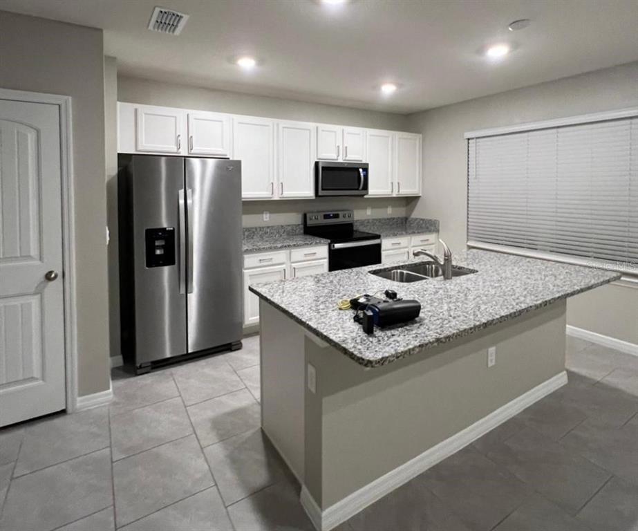 A kitchen features white cabinets, granite countertops, stainless steel appliances, and a central island — 13286 PONTOON RD, WINTER GARDEN, FL