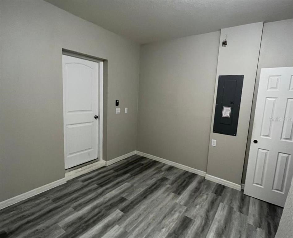 A room with gray walls, wood-look flooring, two white doors, and a black electrical panel — 13286 PONTOON RD, WINTER GARDEN, FL