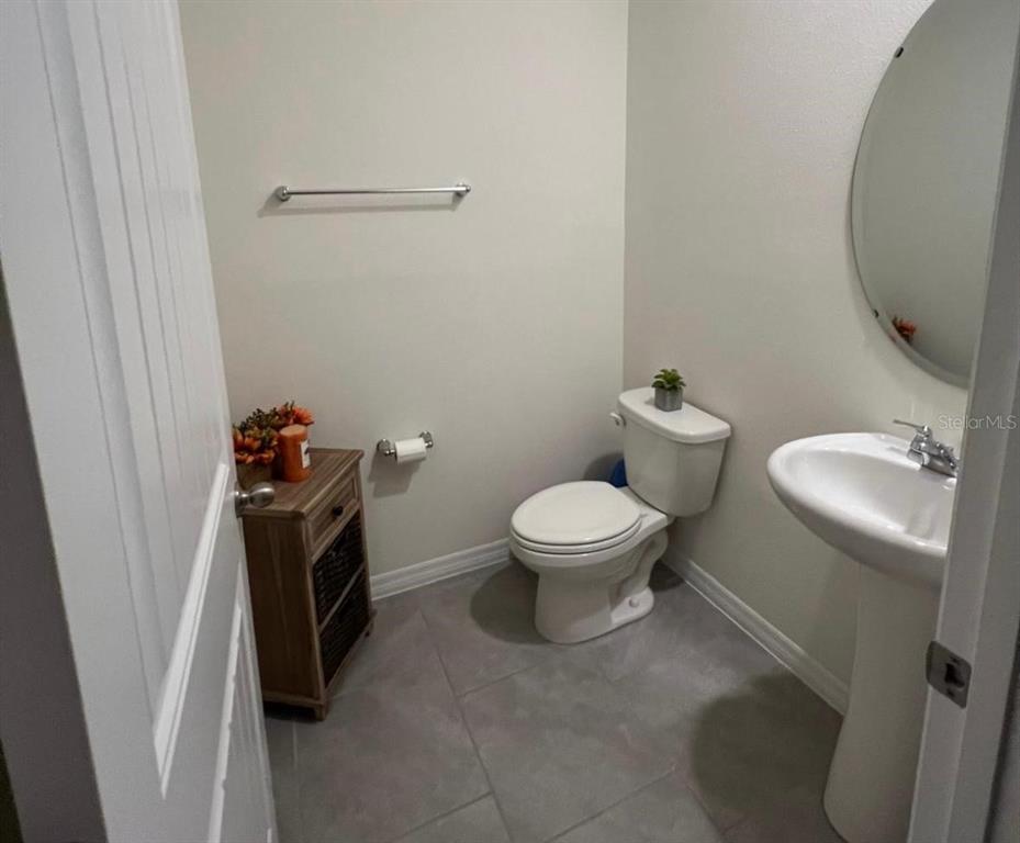 A half bathroom features a pedestal sink, a toilet, and a small wooden storage cabinet — 13286 PONTOON RD, WINTER GARDEN, FL