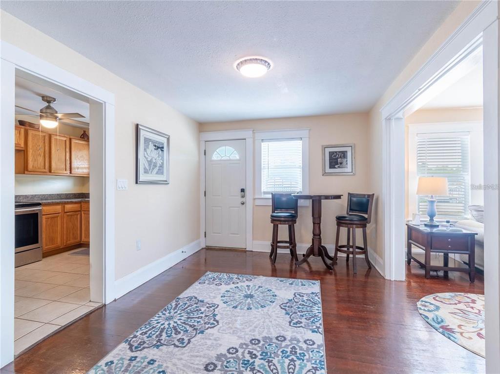 A dining area with hardwood floors, a small bistro table, and an adjacent kitchen — 103 E MOHAWK AVENUE UNIT B, TAMPA, FL