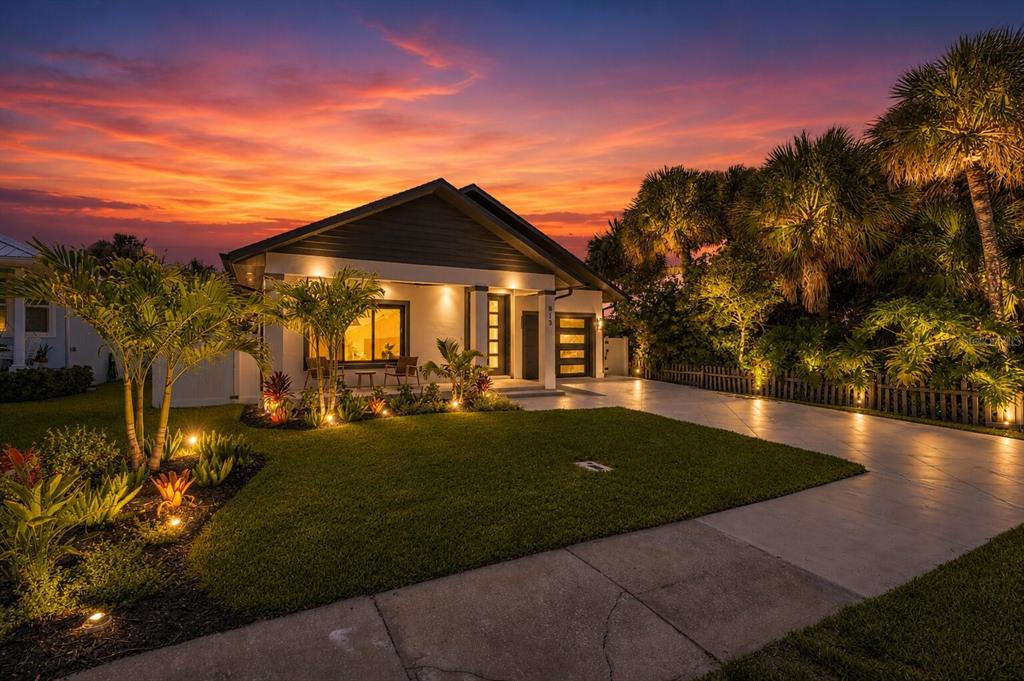 A single-story house with a lit front porch and driveway at sunset — 813 E 1ST AVENUE, NEW SMYRNA BEACH, FL