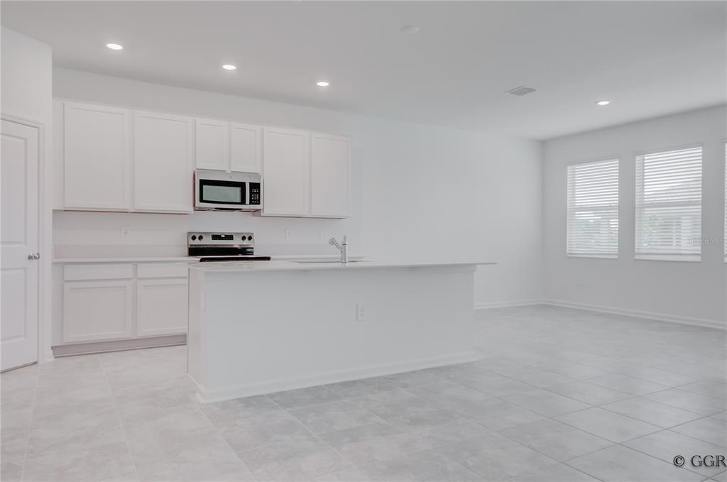 A modern kitchen features white cabinets, stainless steel appliances, and a central island — 1928 ROCK MAPLE BEND, KISSIMMEE, FL