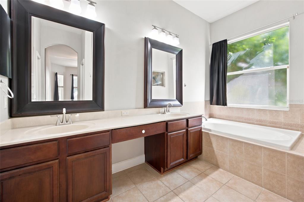A bathroom features a double vanity with dark wood cabinets, two mirrors, and a soaking tub — 5517 GREYSTONE DRIVE, SPRING HILL, FL