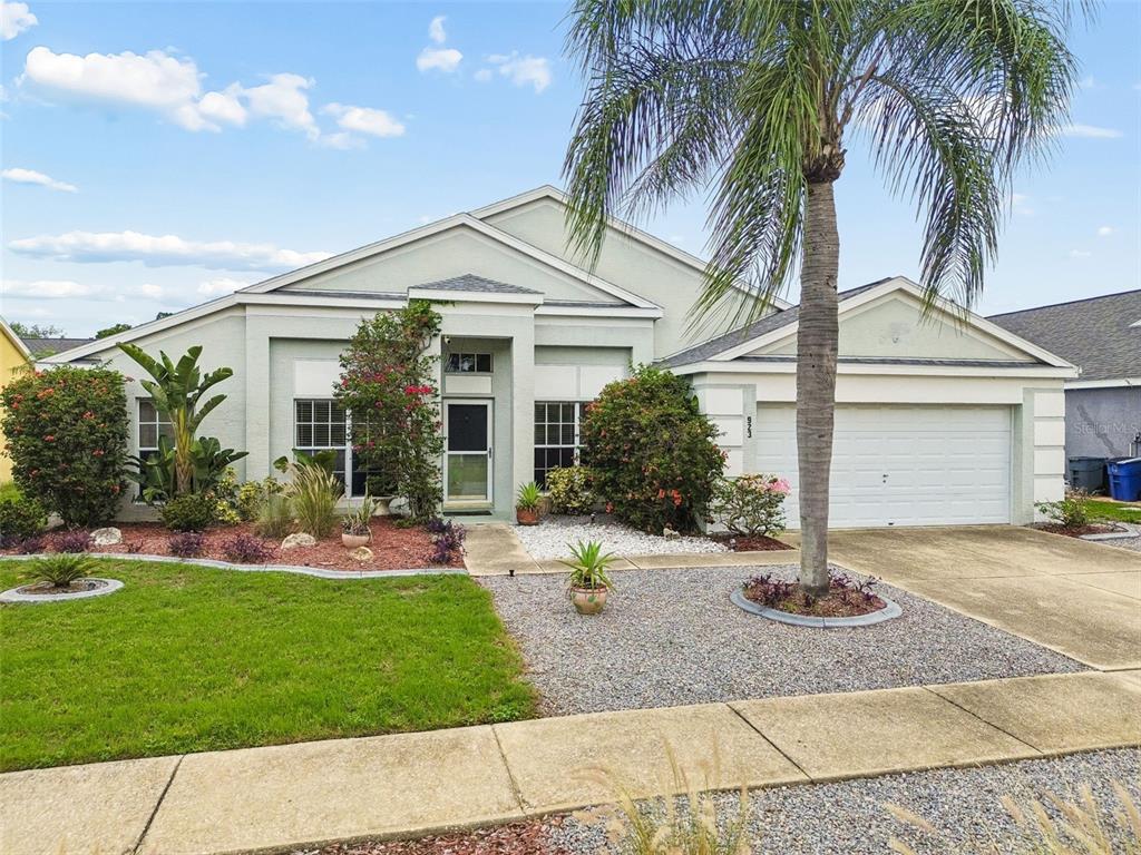 A single-story house with a white garage, a palm tree, and a landscaped front yard — 923 HUNTER LANE, TARPON SPRINGS, FL