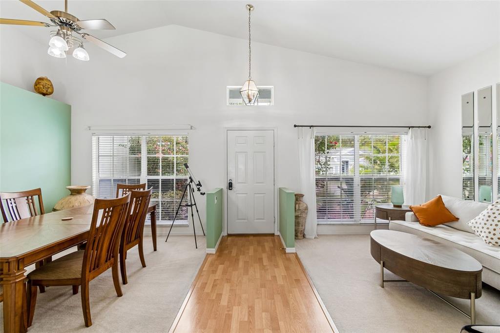 A living and dining area features a vaulted ceiling, wood flooring, and a front entrance — 923 HUNTER LANE, TARPON SPRINGS, FL