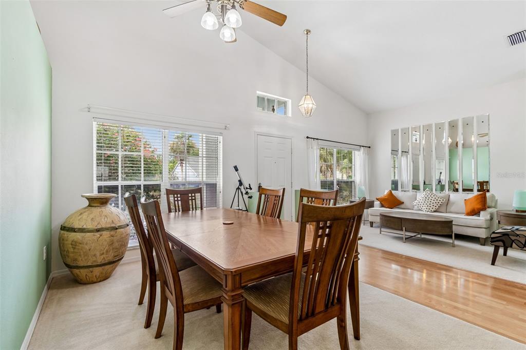 A dining area with a wooden table and chairs sits adjacent to a living room — 923 HUNTER LANE, TARPON SPRINGS, FL