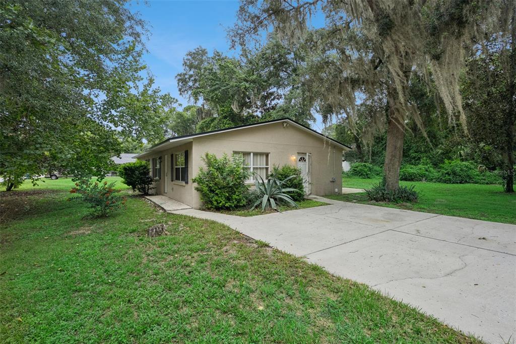 A single-story tan house with a concrete driveway and surrounding trees — 1531 19TH STREET, ORANGE CITY, FL