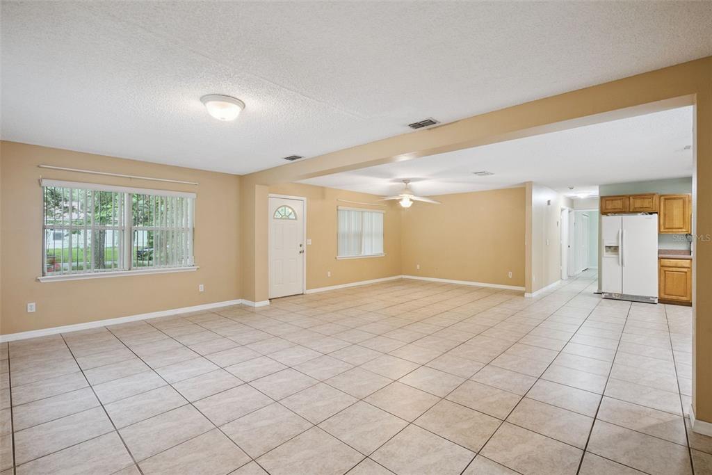 An open-concept living area features tan walls, beige tile flooring, and a white kitchen — 1531 19TH STREET, ORANGE CITY, FL