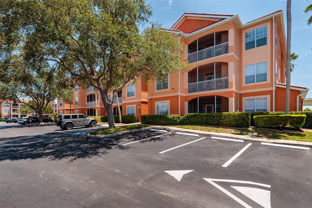 A three-story orange apartment building with screened balconies sits behind a paved parking lot — 5000 CULBREATH KEY WAY UNIT 4-105, TAMPA, FL