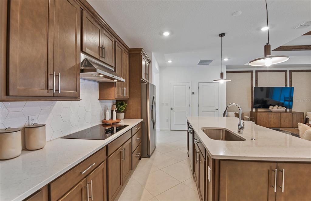 A kitchen features brown wooden cabinets, white countertops, a central island, and stainless steel appliances — 8169 SW 44TH COURT ROAD, OCALA, FL