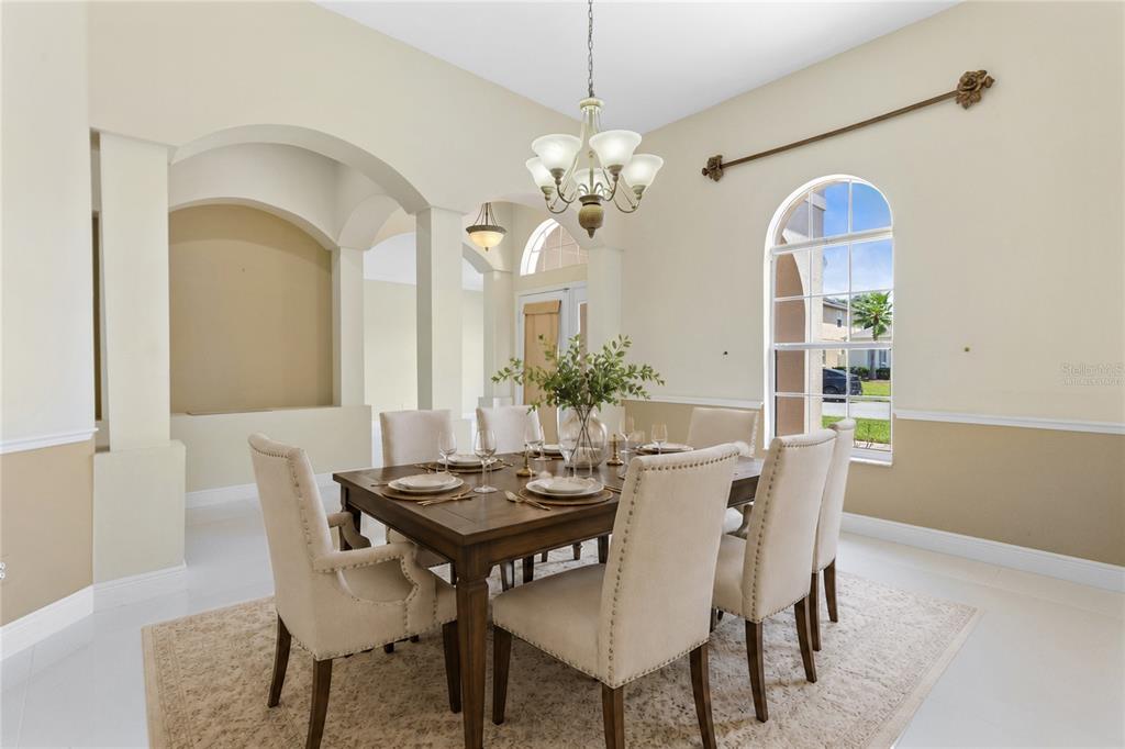 A formal dining room features a wooden table, upholstered chairs, and a large arched window — 856 TIMBER ISLE DRIVE, ORLANDO, FL
