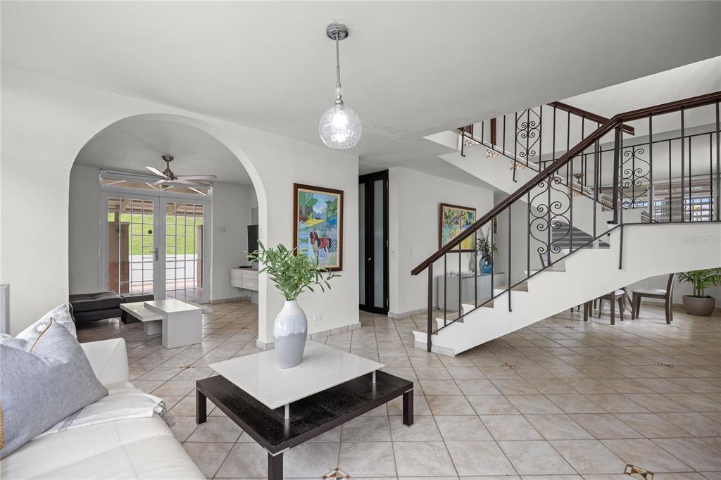 A bright living area features tile floors, an arched entryway, and a decorative staircase — Calle 6 H17 TINTILLO GARDENS, GUAYNABO, PR