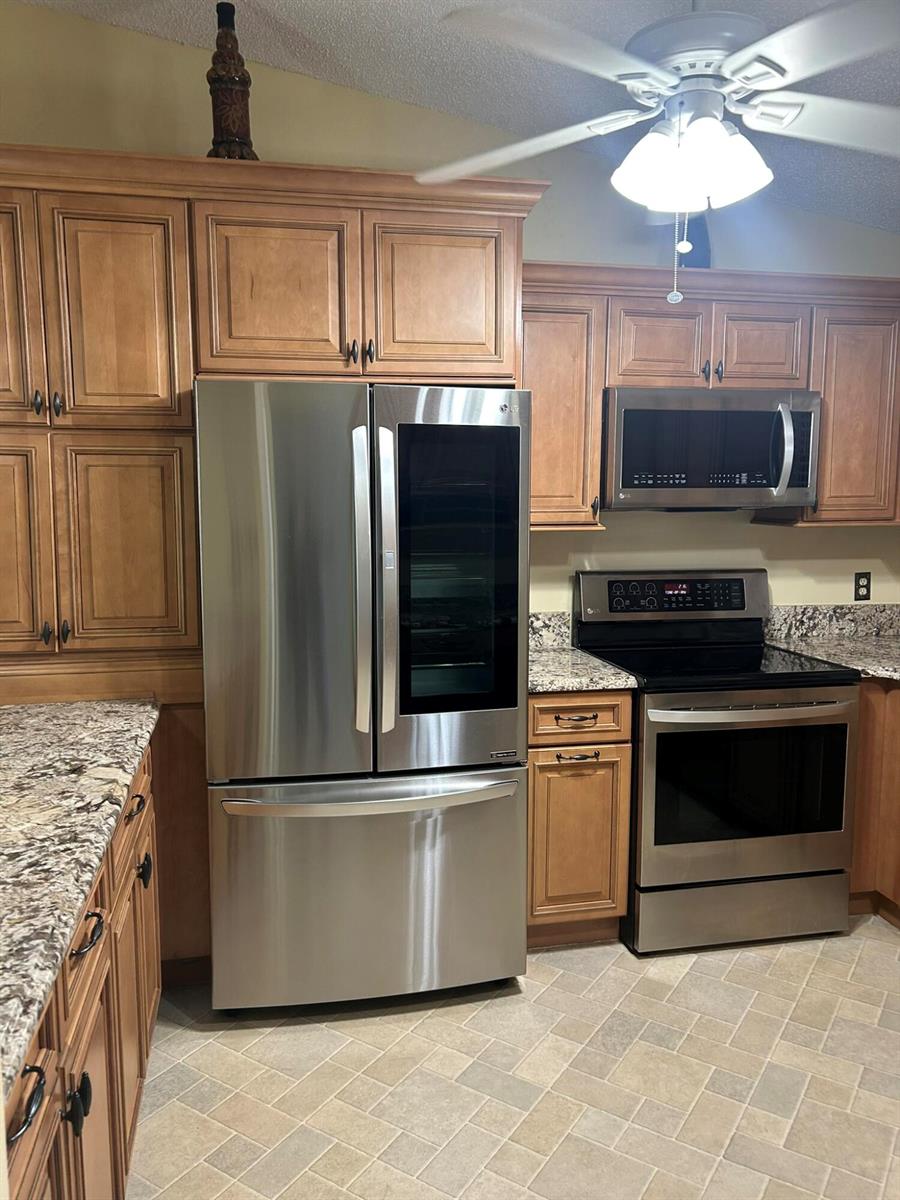 A kitchen features wood cabinets, stainless steel appliances, and granite countertops — 3001 SE Aster Lane # 908, Stuart FL 34994, STUART, FL