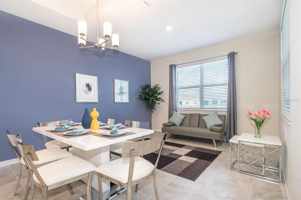 A dining room features a white table, blue accent wall, and a small gray sofa — 3180 PARADOX CIRCLE UNIT 405, KISSIMMEE, FL