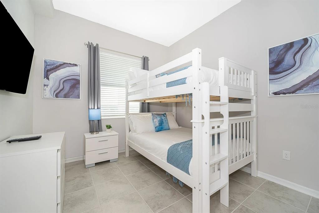 A bedroom features a white bunk bed, a dresser, and a window with gray curtains — 3180 PARADOX CIRCLE UNIT 405, KISSIMMEE, FL