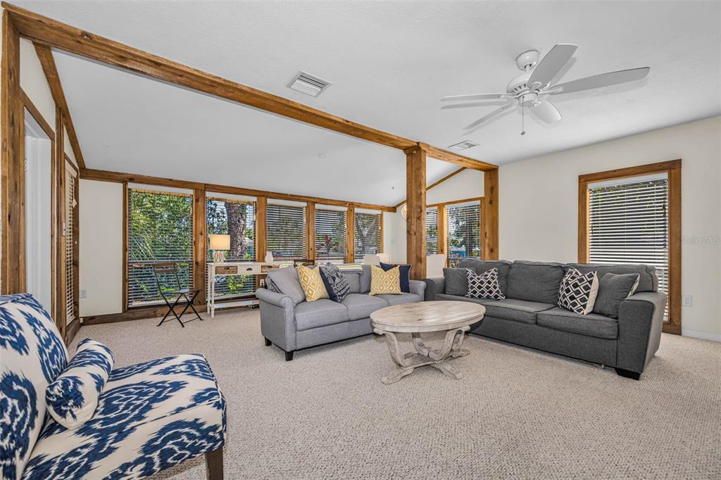 A living room features two gray sofas, a round wooden coffee table, and exposed beams — 525 BAY STREET, DUNEDIN, FL