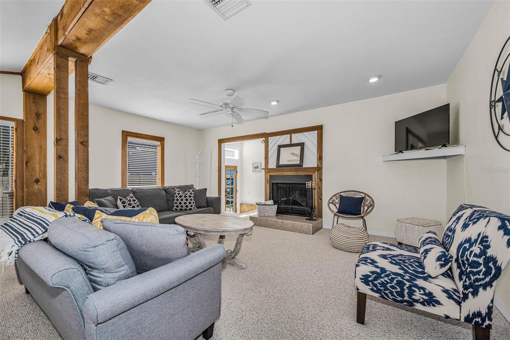 A living room features a fireplace, a ceiling fan, and a mix of patterned furniture — 525 BAY STREET, DUNEDIN, FL