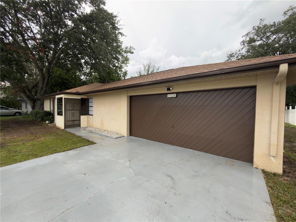A single-story house exterior features a two-car garage with a brown diagonal-slat door — 15120 SW 35TH CIRCLE, OCALA, FL