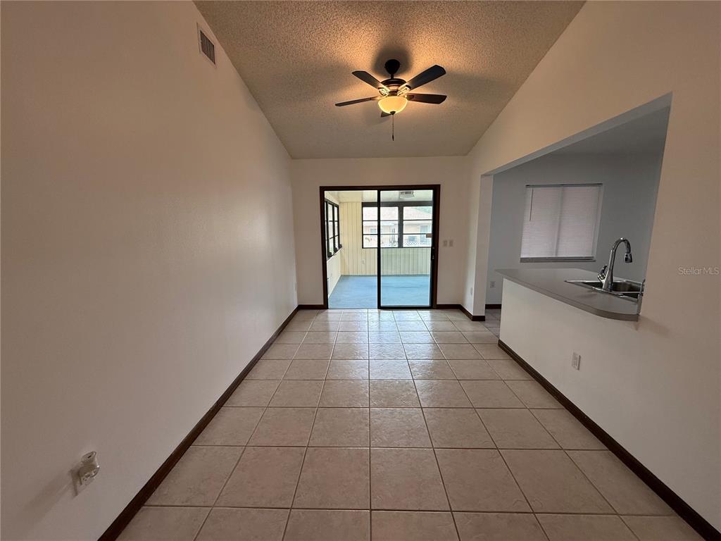 A dining area with tile flooring leads to a sliding glass door and a kitchen — 15120 SW 35TH CIRCLE, OCALA, FL