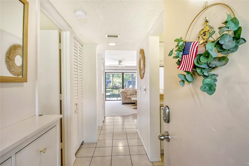 An entryway with tiled floors leads to a living area with a view of a balcony — 4616 RINGWOOD MEADOW UNIT 20, SARASOTA, FL