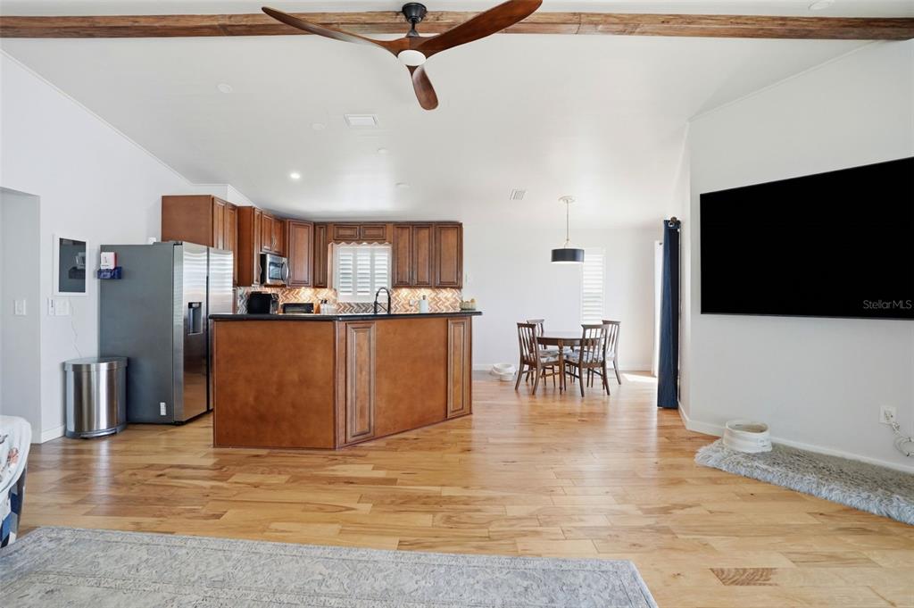 An open-concept kitchen and dining area features wood cabinets, a central island, and hardwood floors — 3420 EAGLE NEST DRIVE, HERNANDO BEACH, FL
