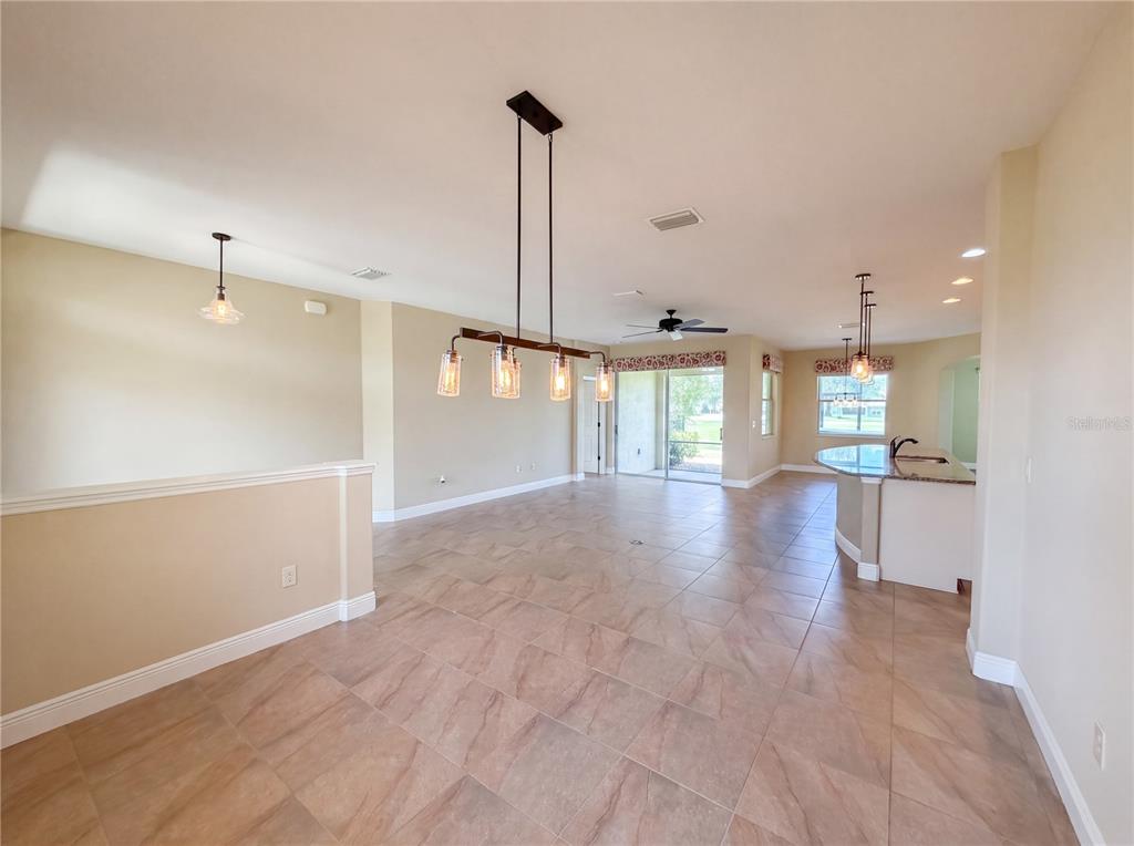 An open-concept living and dining area features tile flooring, a kitchen island, and pendant lighting — 27103 CAMERONS RUN, LEESBURG, FL