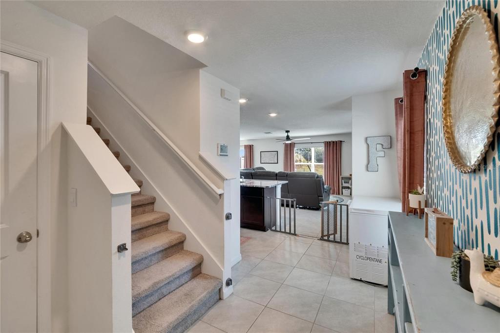 A staircase with carpeted steps leads to an open-concept living area with tile flooring — 16894 DELIA STREET, WIMAUMA, FL