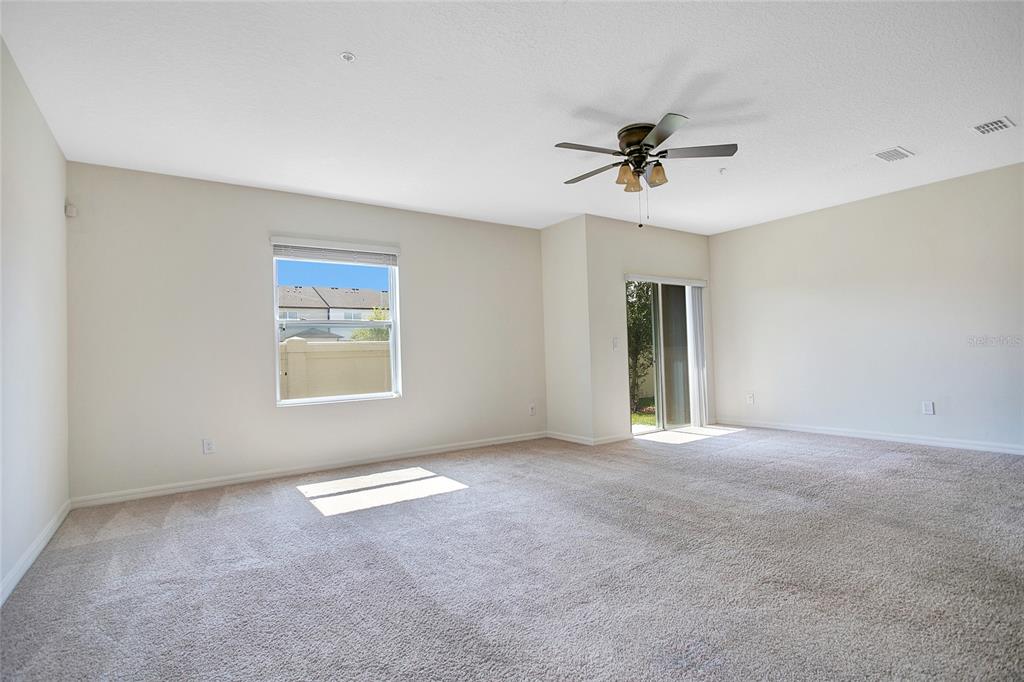 An empty room with beige carpet, a ceiling fan, a window, and sliding glass doors — 3521 SENECA CLUB LOOP UNIT 103C, ORLANDO, FL