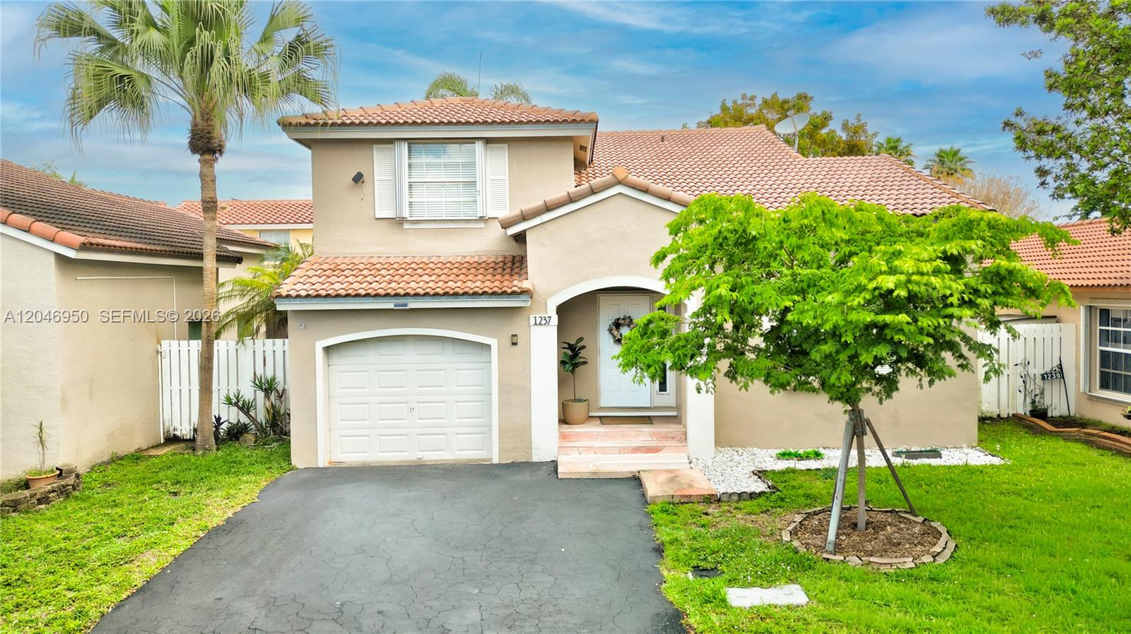 A two-story house features a tan stucco exterior, a tiled roof, and a front garage — 1237 NW 125th Ter, Sunrise FL 33323, SUNRISE, FL