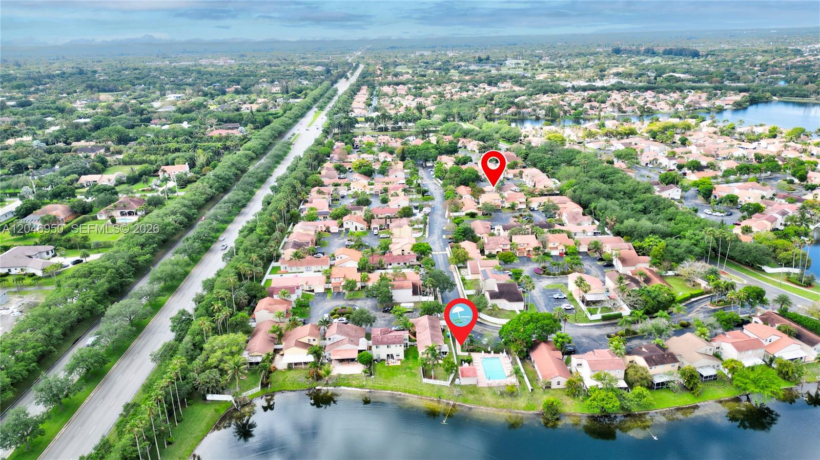 This aerial view shows a residential neighborhood with a community pool and a lake — 1237 NW 125th Ter, Sunrise FL 33323, SUNRISE, FL