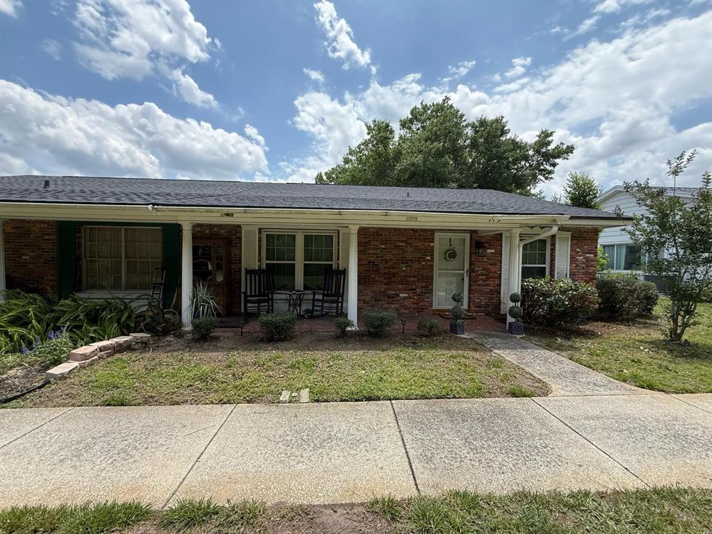A single-story brick house features a covered front porch with rocking chairs and a walkway — 719 AVENUE Q SE, WINTER HAVEN, FL