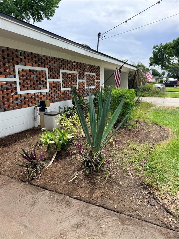 A brick-walled house exterior features a large agave plant in a mulched garden bed — 719 AVENUE Q SE, WINTER HAVEN, FL