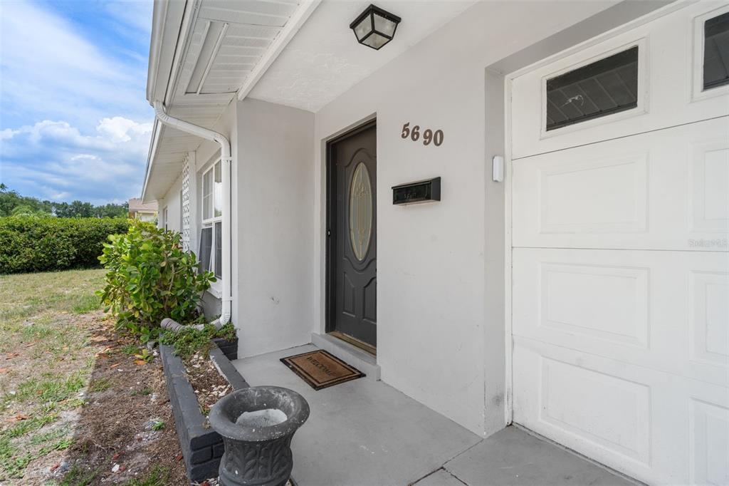 A gray front door with a glass insert sits beside a white garage door — 5690 6TH STREET S, ST PETERSBURG, FL