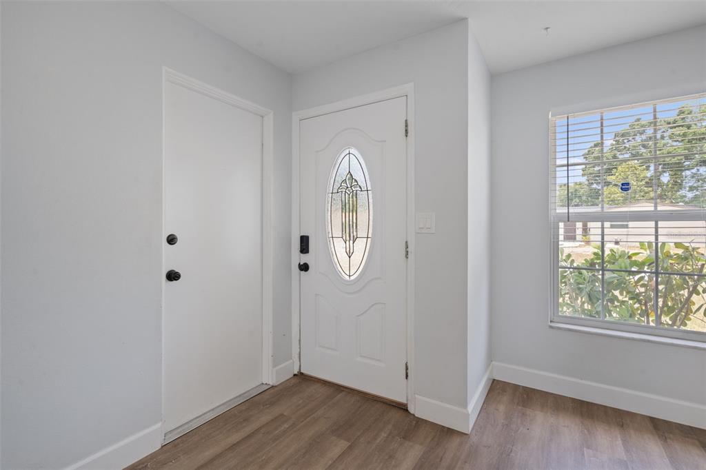An entryway features light gray walls, wood-look flooring, a white front door, and a window — 5690 6TH STREET S, ST PETERSBURG, FL