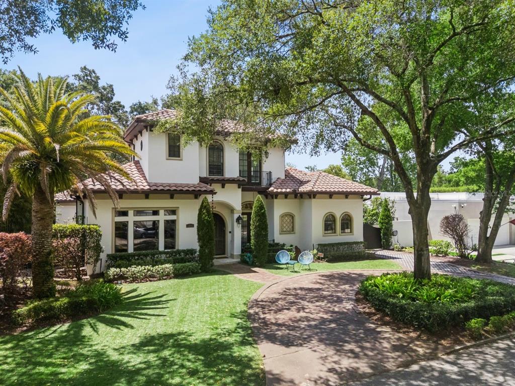 A two-story Mediterranean-style house features a tiled roof, stucco exterior, and a curved driveway — 1864 GRINNELL TERRACE, WINTER PARK, FL