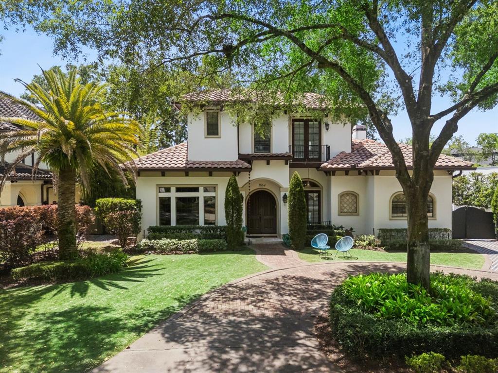 A two-story stucco house with a tile roof, arched entryway, and a circular driveway — 1864 GRINNELL TERRACE, WINTER PARK, FL