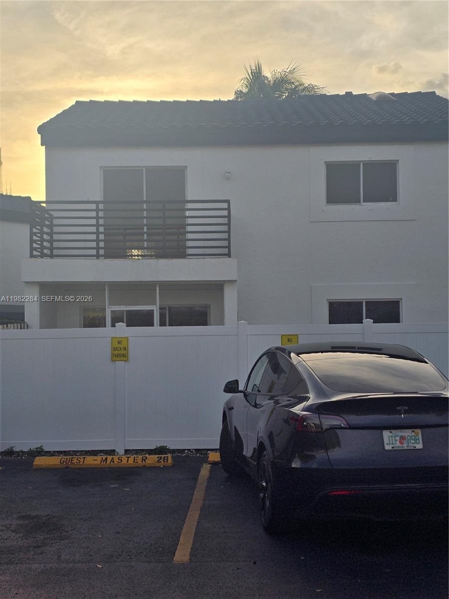 A two-story building exterior features a balcony, white walls, and a parking space — 252 NE 212th Ter, Miami FL 33179, MIAMI, FL
