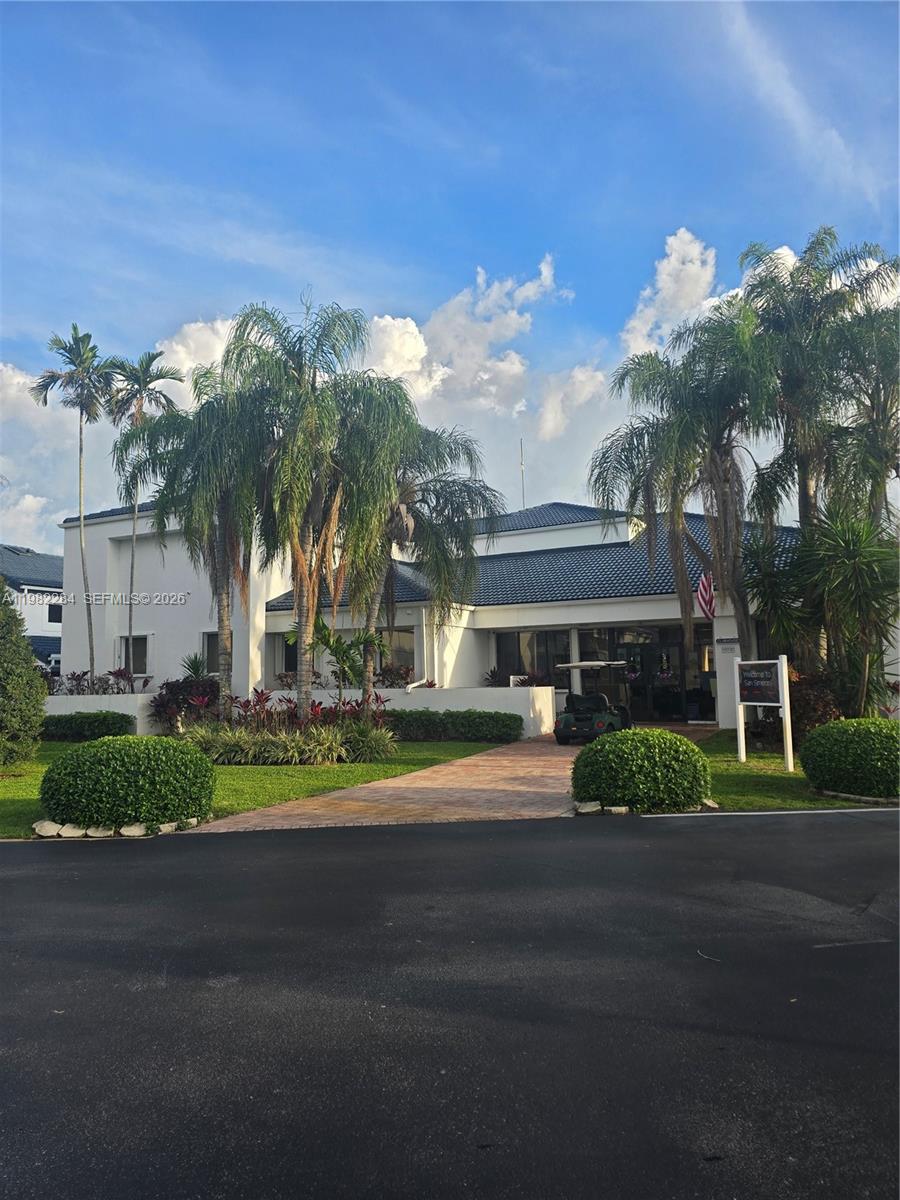 A white building with a dark tiled roof is surrounded by palm trees and landscaping — 252 NE 212th Ter, Miami FL 33179, MIAMI, FL