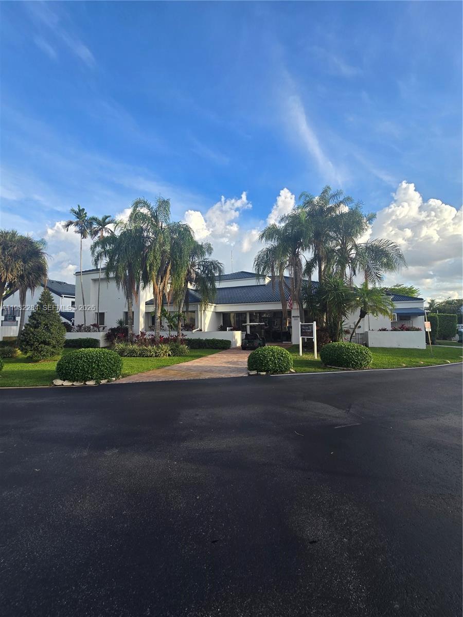 A white building with a blue tile roof sits behind a paved driveway and landscaping — 252 NE 212th Ter, Miami FL 33179, MIAMI, FL