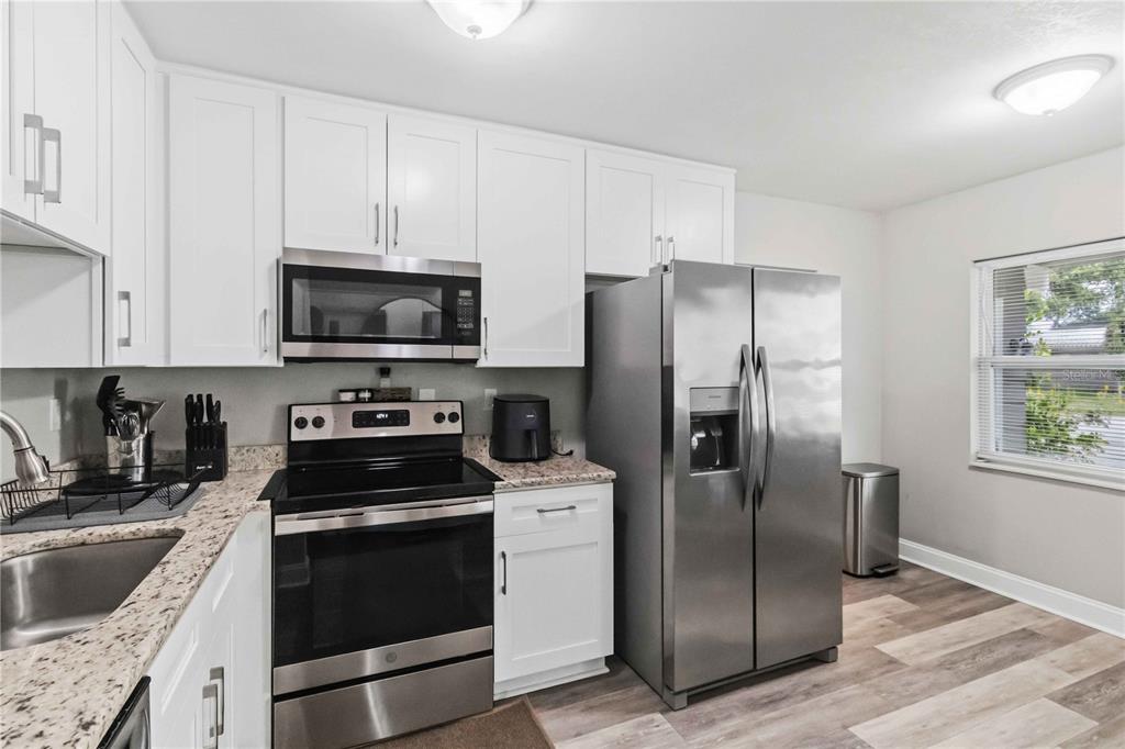 A kitchen with white cabinets, stainless steel appliances, and granite countertops — 7012 40TH AVENUE N, ST PETERSBURG, FL