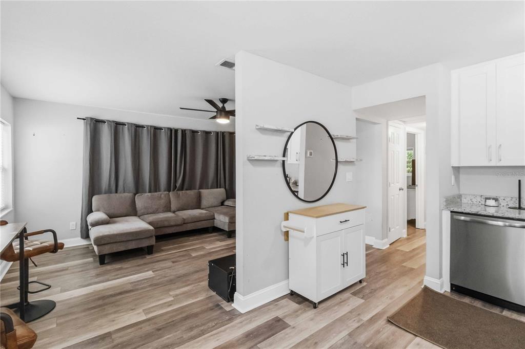 A living room with a sectional sofa and a kitchen area with white cabinets — 7012 40TH AVENUE N, ST PETERSBURG, FL