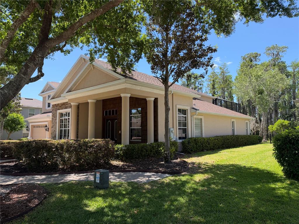 A beige single-story house features a columned front porch and a paved walkway — 21430 DRAYCOTT WAY, LAND O LAKES, FL