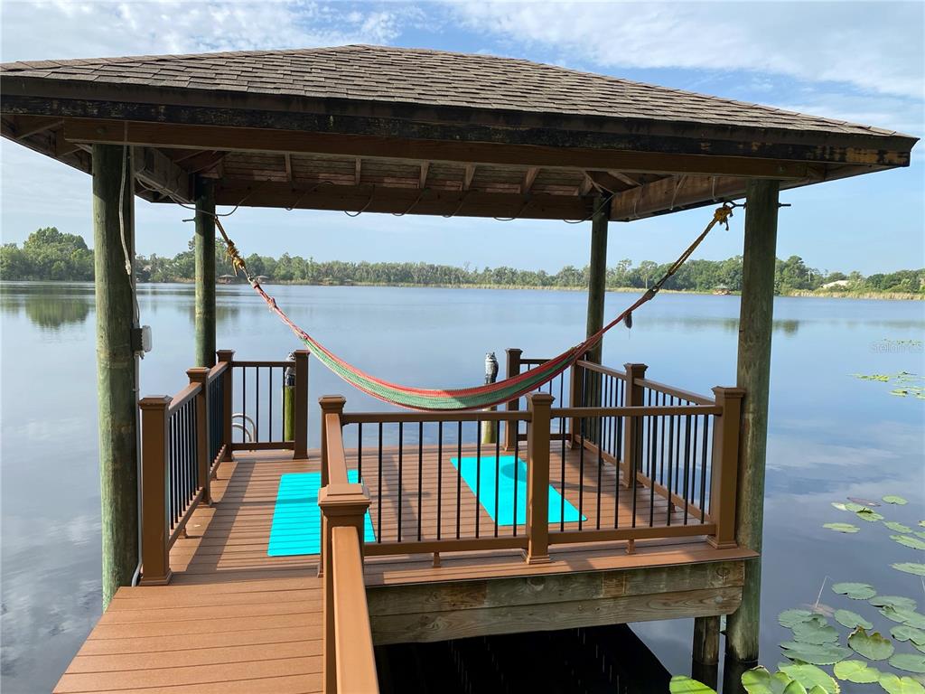 A wooden gazebo with a hammock sits on a dock overlooking a calm lake — 21430 DRAYCOTT WAY, LAND O LAKES, FL
