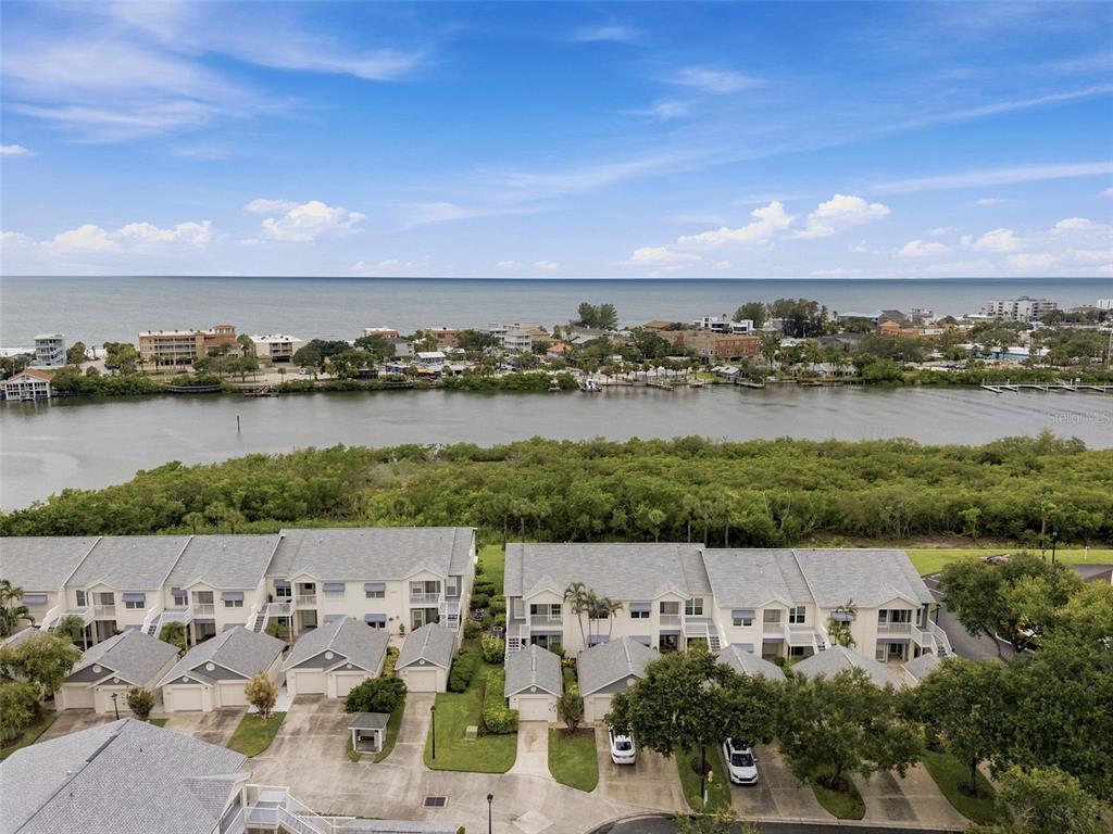 An aerial view shows townhomes with gray roofs situated near a waterway and the ocean — 11541 SHIPWATCH DRIVE UNIT 1011, LARGO, FL
