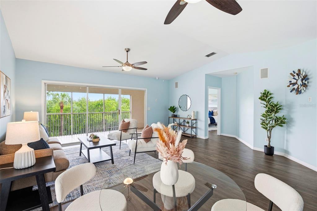 A bright living and dining area features light blue walls, wood flooring, and a balcony — 11541 SHIPWATCH DRIVE UNIT 1011, LARGO, FL