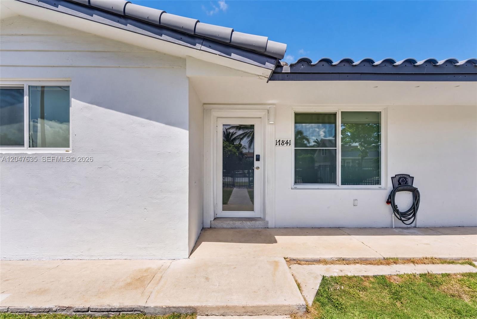The exterior of a white house features a glass front door and a tiled roof — 17841 SW 112th Pl, Miami FL 33157, MIAMI, FL