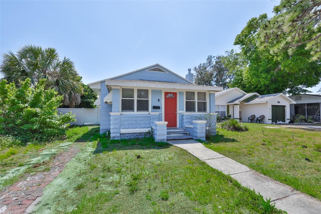 A light blue bungalow with a red front door and a stone-textured porch base — 4736 5TH AVENUE S, ST PETERSBURG, FL