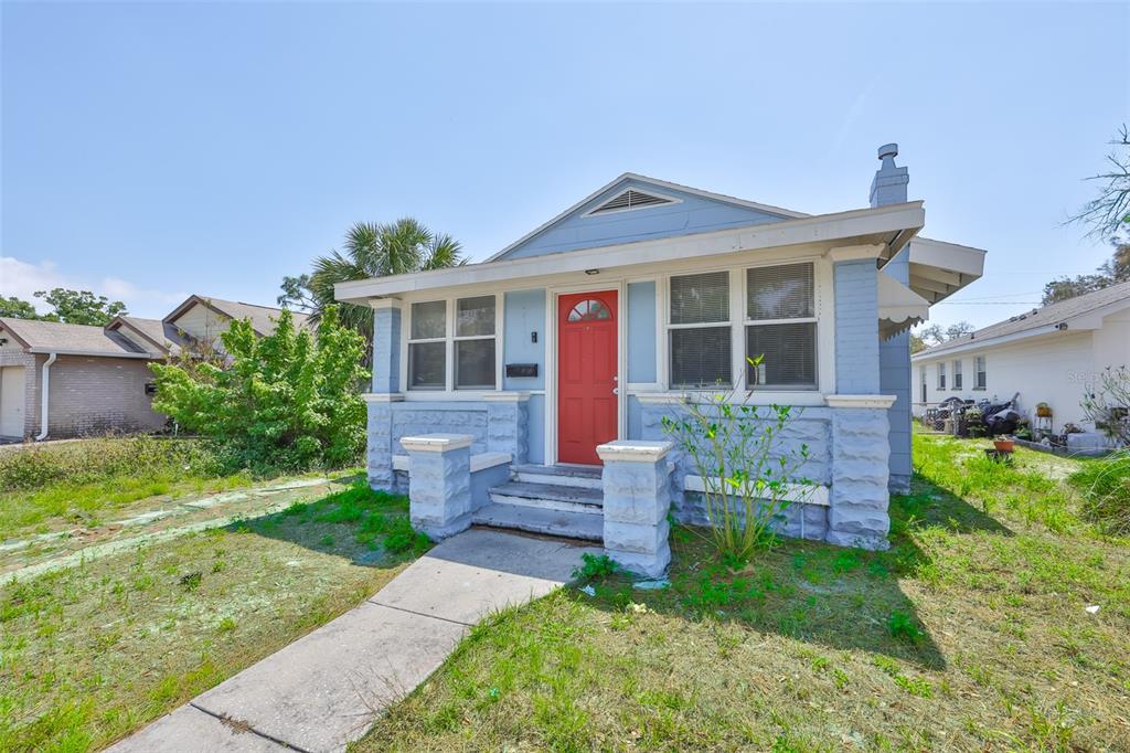 A light blue bungalow with a red front door and a concrete walkway — 4736 5TH AVENUE S, ST PETERSBURG, FL