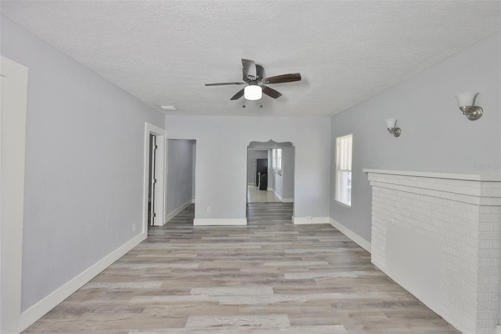 A living room with light gray walls, wood-look flooring, a ceiling fan, and a fireplace — 4736 5TH AVENUE S, ST PETERSBURG, FL
